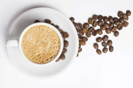 Delicious breakfast cup of coffee top view with foam and roasted bean decoration.