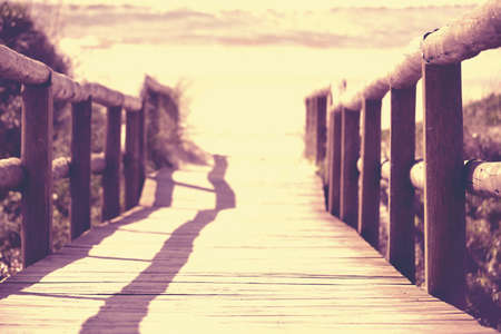 Perspective view of wood bridge on the beach with sea and sand in the background, vintage filter effect.の写真素材