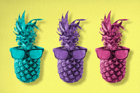 Three trendy pineapple fruits wearing cool hipster sunglasses in colorful retro style, happy summer concept background art.の写真素材