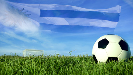 Soccer ball with Uruguay flag for sport event, Uruguayan team celebration. Realistic leather football on goal post field over blue sky background.の写真素材
