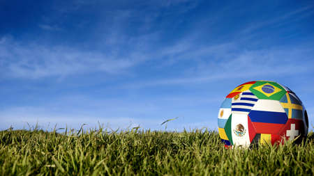 Soccer ball with international country flag of russian sport event groups. Realistic football on grass field over blue sky background. Includes russia, brazil, mexico and more.の写真素材