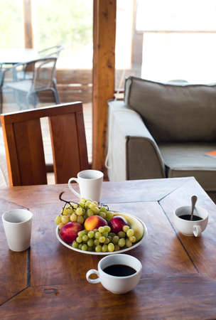 Breakfast food at home, healthy summer holiday eating. Fruit bowl on wood table with apple, grapes, peach and coffee drink.の写真素材