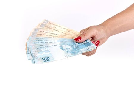 Woman's hand holding Brazilian money on white backgroundの写真素材