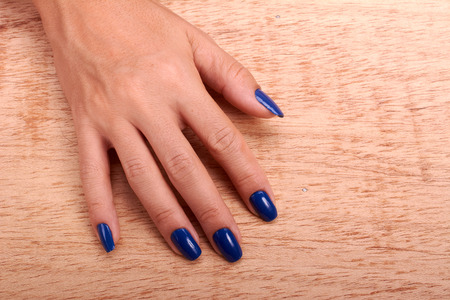 woman hands and nails blue care of manicure in wood backgroundの写真素材