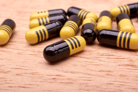 Capsules or pills yellow and black of medicament on wood background