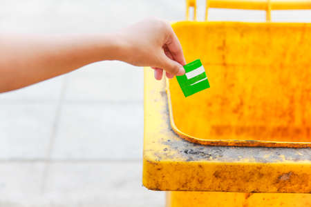 Female hand throwing green plastic  into the trashの写真素材