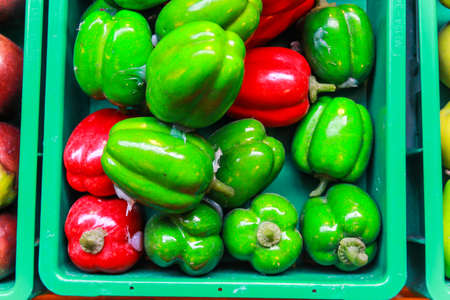 red and green sweet peppers in plastic containerの写真素材