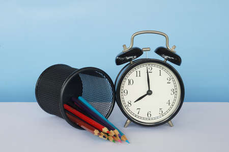 alarm clock and pencils on the tableの写真素材