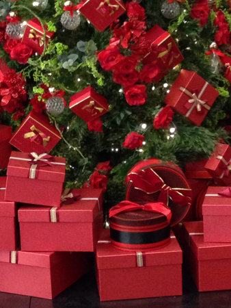 Bunch of red gift boxes against green Christmas tree.