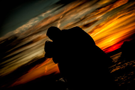 Groom silhouette at sunset under dramatic summer sky