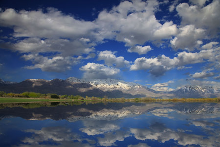 Rocky Mountains in the spring showing trees and snow capped mountainsi with tefelections in a lake