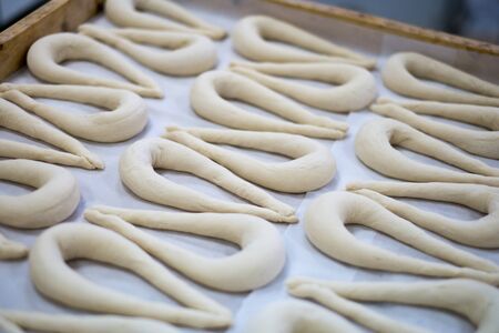 Freshly made Pretzel Dough ( Also known as a Brezel or Breze) on a tray shot at a local bakery factory. Raw uncooked dough shown on a wax sheet on a wooden tray.の写真素材