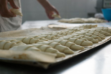 A local baker putting freshly rolled croissants onto a tray prepping them to be baked.の写真素材