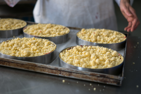 Pastry chef showing off finished cherry filled pies with cookie crumble topping and graham crackers crust.の写真素材