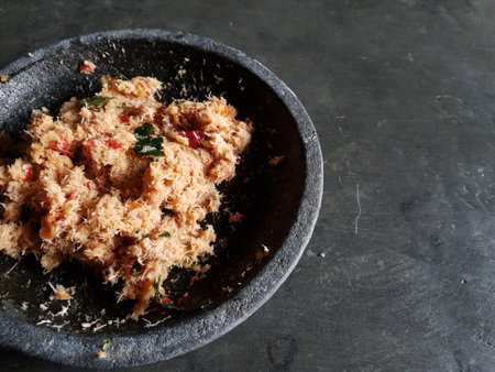 Grated coconut is mixed with spices consisting of garlic, chili, sugar, palm sugar, salt and lime leaves. The taste is spicy and savory with a little sweetness, very good when mixed with vegetables. Very suitable for dieting. In this photo, grated coconut is served on a black stone plate.の写真素材