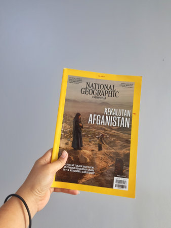 West Java in August 2022. A hand holds the Indonesian version of the National Geographic magazine. National Geographic is the official journal of the National Geographic Society which has provided information about the world and all its contents globally のeditorial素材