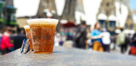 Osaka, Japan on April 10, 2022. Butterbeer drink in a plastic cup on a blurred background. This drink is a signature drink from Hogwarts, a sweet soda with a butter-flavored foam.のeditorial素材