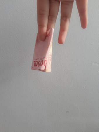 Isolated photo of a hand holding a hundred thousand rupiah banknote. The largest denomination of rupiah. With negative space, this photo can be used for the concept of alms or charity.の写真素材