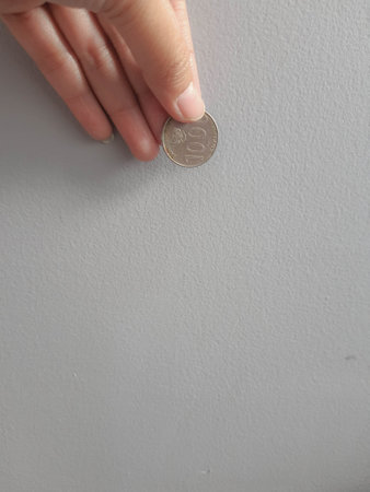 Isolated photo of a hand holding a thousand rupiah coin. This coin is usually used to pay for the averse or parking attendant or given to beggars or charity.の写真素材