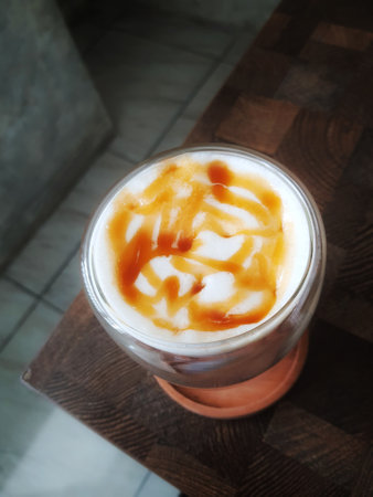 Glass of Ice Salted Caramel Macchiato. Coffee with a mixture of milk and caramel syrup which is very fresh, sweet, slightly bitter and salty is very delicious enjoyed on a hot day.の写真素材