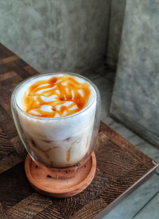 Glass of Ice Salted Caramel Macchiato. Coffee with a mixture of milk and caramel syrup which is very fresh, sweet, slightly bitter and salty is very delicious enjoyed on a hot day.の写真素材