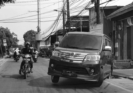 Jakarta, Indonesia in August 2022. A car has fallen into a sewer on the side of the road in a densely populated village in Jakarta. Causing the road to be blocked and jammed.のeditorial素材