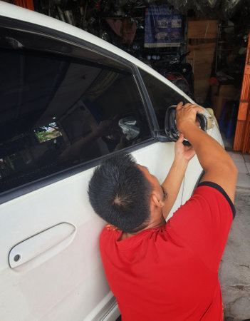 West Java, Indonesia in September 2022. A repairman is installing a new rearview mirror because the old one is broken.のeditorial素材