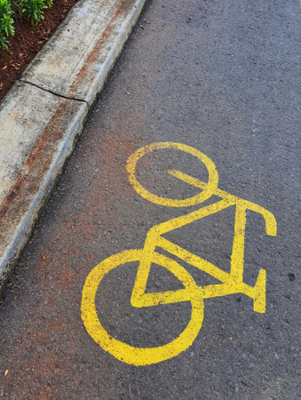 Bicycle lane sign in yellow with solid lines on asphalt road in Indonesia. Drivers should not cross into them unless you're turning or parking, and be sure to yield to bikes first.の写真素材