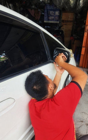 West Java, Indonesia in September 2022. A repairman is installing a new rearview mirror because the old one is broken.のeditorial素材