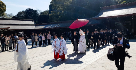Japan on April 2019. A Japanese Shinto wedding ceremony process at Meiji Shrine. The groom wears a black kimono and the bride wears a white kimono. It is very attractive to tourists who are visiting Meiji Shrine.のeditorial素材