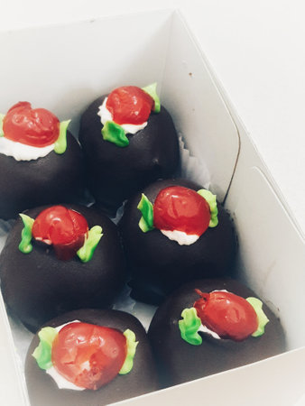 A box of mini black forest cakes, cake with chocolate coating and cherry fruit topping on top. These small shapes are perfect for afternoon snacks with tea.の写真素材