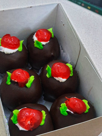 A box of mini black forest cakes, cake with chocolate coating and cherry fruit topping on top. These small shapes are perfect for afternoon snacks with tea.の写真素材