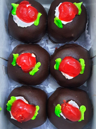A box of mini black forest cakes, cake with chocolate coating and cherry fruit topping on top. These small shapes are perfect for afternoon snacks with tea.の写真素材
