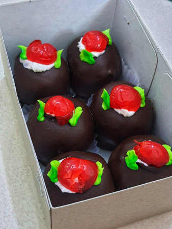 A box of mini black forest cakes, cake with chocolate coating and cherry fruit topping on top. These small shapes are perfect for afternoon snacks with tea.の写真素材