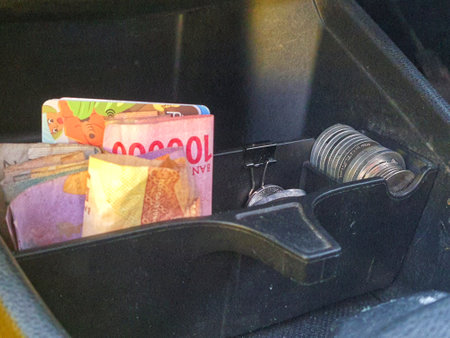 Some rupiah coins and one hundred thousand rupiah notes and some other money in a box provided on the dashboard of the car which functions as a place for coins.の写真素材