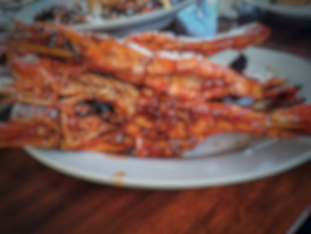 Blur or defocused photo of three freshly cooked honey grilled prawns that look absolutely delicious, sitting on a wooden cutting board.の写真素材