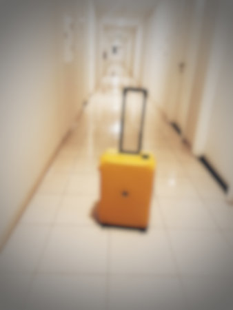 Defocused blurred photo of a yellow suitcase in an apartment hallway.の写真素材