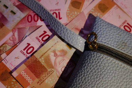 A blue wallet or blue leather pouch on top of which several hundred thousand rupiah bills are scattered. It is perfect for your template background, or for news related to fashion, business and finance.の写真素材