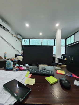 Jakarta, Indonesia in July 2022. An office desk in a project site office, there is a computer monitor along with its keyboard and several sticky notes and other documents.の写真素材