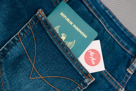 Indonesia in July 2022. An Indonesian citizenship passport and an Air Asia Airlines boarding pass in a jeans pocket. This photo is suitable as an illustration of traveling abroad.のeditorial素材