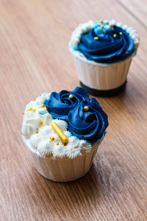 Luxurious and elegant cupcakes, with white cream and navy blue with gold sprinkles. It has a sweet and creamy taste.の写真素材