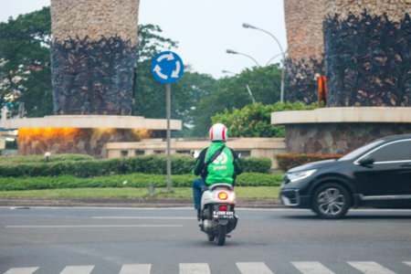 Jakarta, Indonesia in November 2022. Back view of a motorcyclist driving on a busy street on the outskirts of Jakarta.のeditorial素材