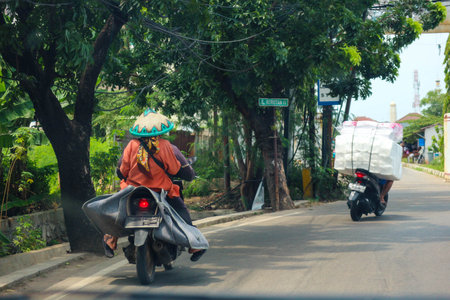 Jakarta, Indonesia in November 2022. Back view of a motorcyclist driving on a busy street on the outskirts of Jakarta.のeditorial素材