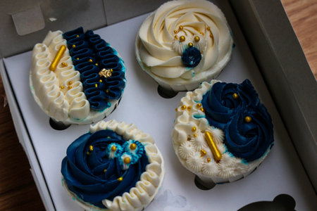 Luxurious and elegant cupcakes, with white cream and navy blue with gold sprinkles. It has a sweet and creamy taste.の写真素材
