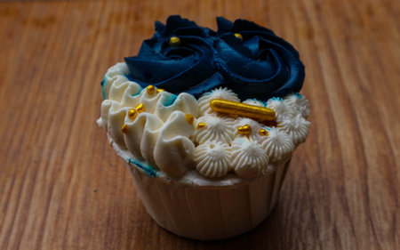 Luxurious and elegant cupcakes, with white cream and navy blue with gold sprinkles. It has a sweet and creamy taste.の写真素材
