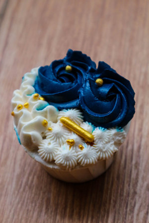 Luxurious and elegant cupcakes, with white cream and navy blue with gold sprinkles. It has a sweet and creamy taste.の写真素材