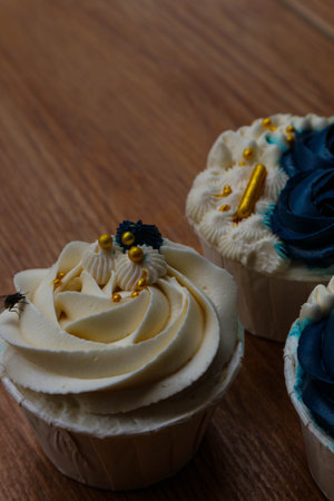 Luxurious and elegant cupcakes, with white cream and navy blue with gold sprinkles. It has a sweet and creamy taste.の写真素材