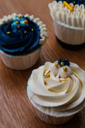 Luxurious and elegant cupcakes, with white cream and navy blue with gold sprinkles. It has a sweet and creamy taste.の写真素材