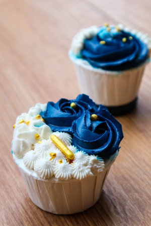 Luxurious and elegant cupcakes, with white cream and navy blue with gold sprinkles. It has a sweet and creamy taste.の写真素材