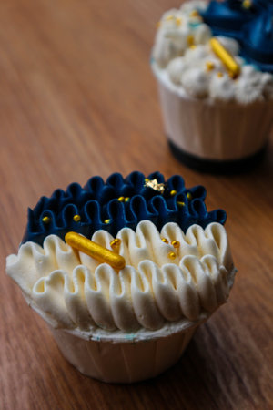 Luxurious and elegant cupcakes, with white cream and navy blue with gold sprinkles. It has a sweet and creamy taste.の写真素材
